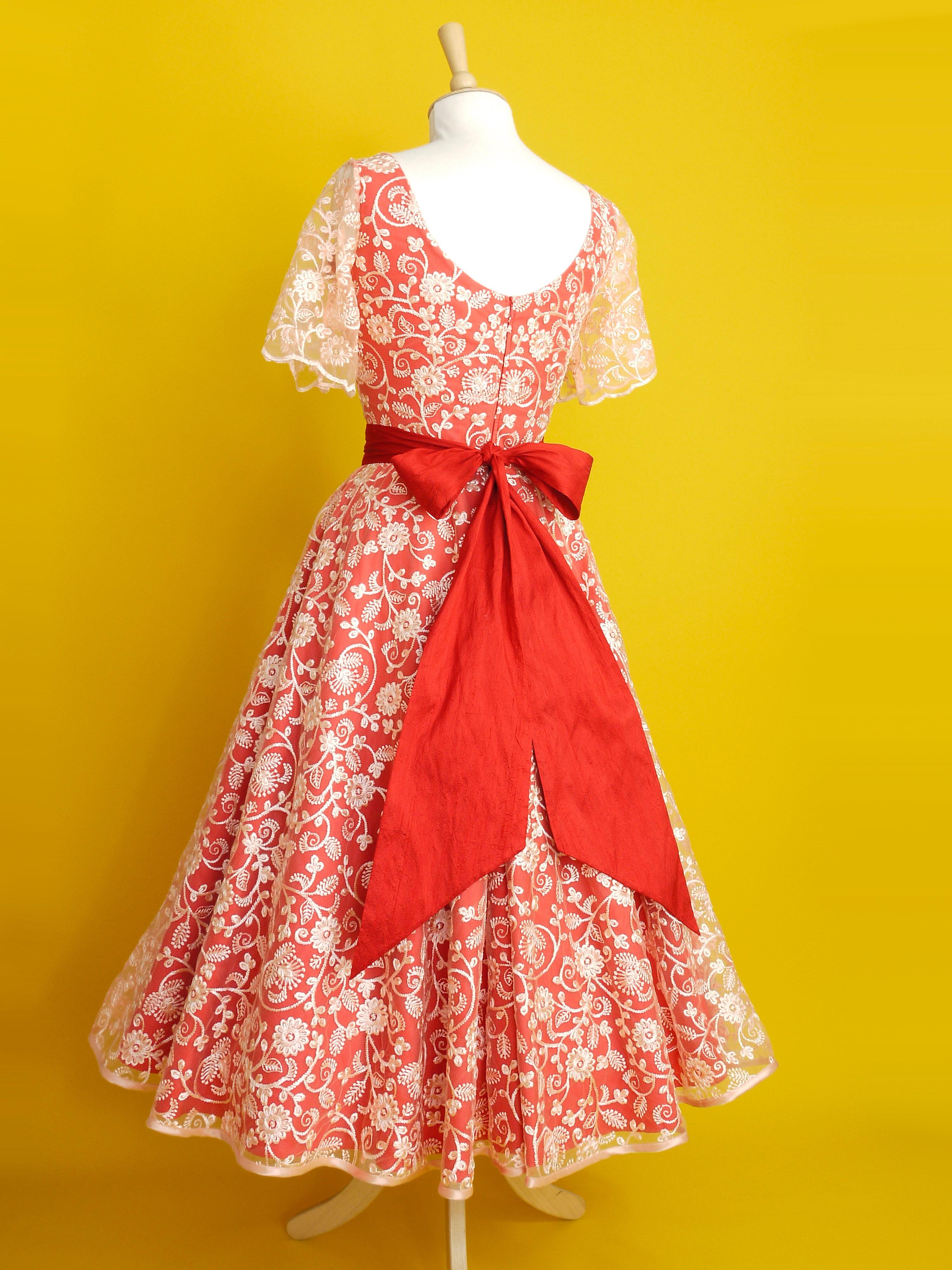 A red and peach lace dress with sleeves and a midi length circle skirt
