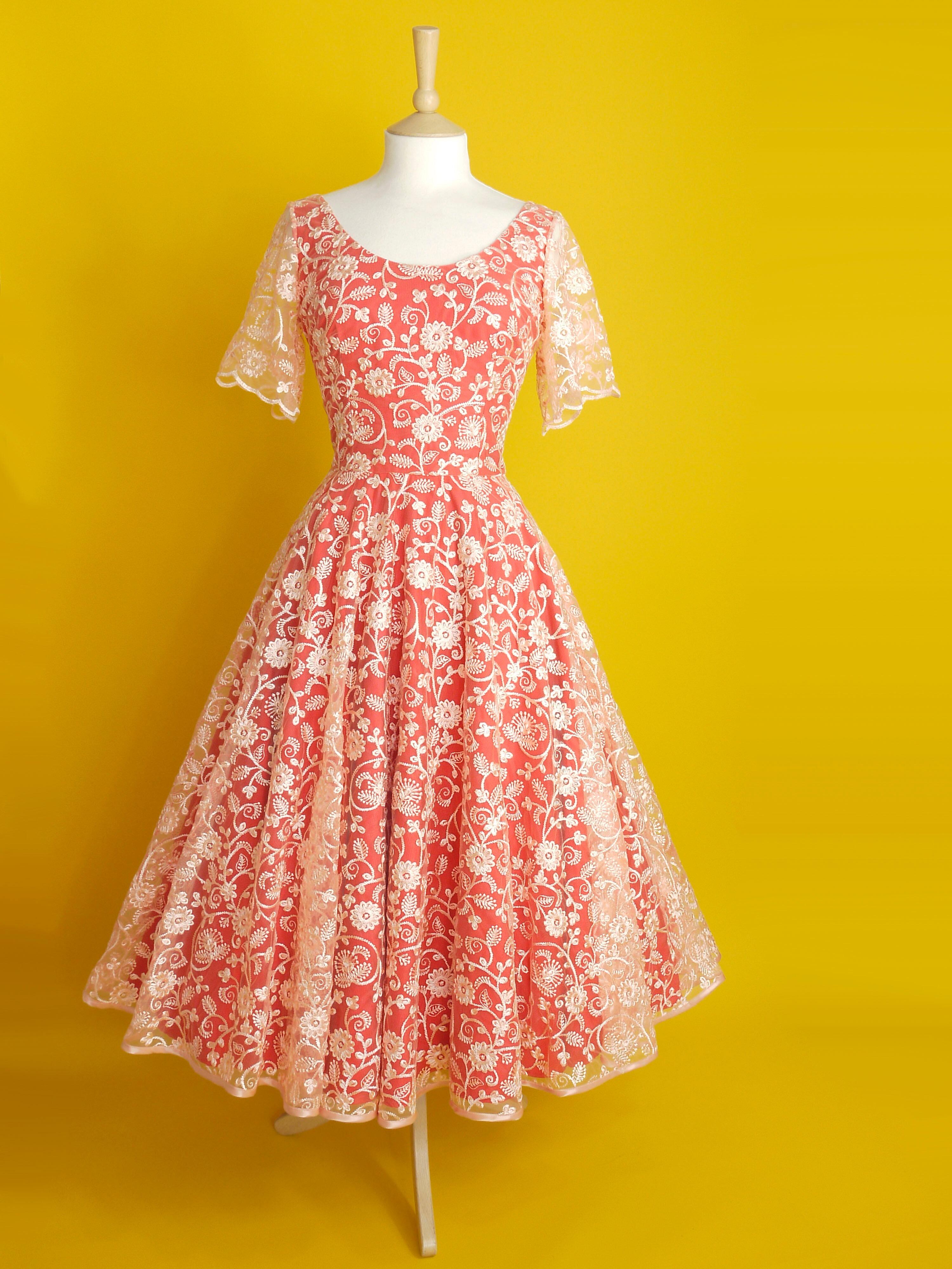 A red and peach lace dress with sleeves and a midi length circle skirt