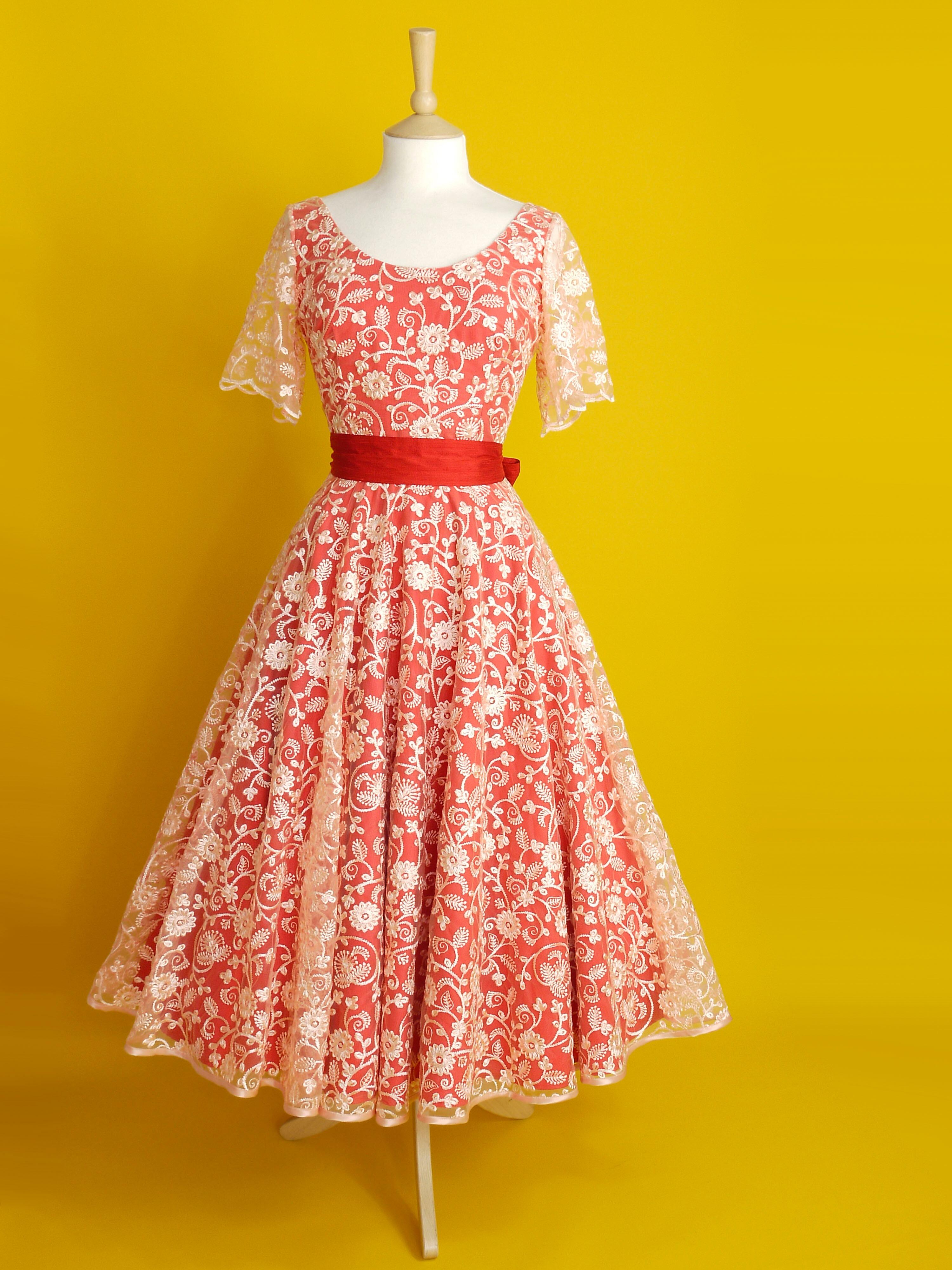 A red and peach lace dress with sleeves and a midi length circle skirt