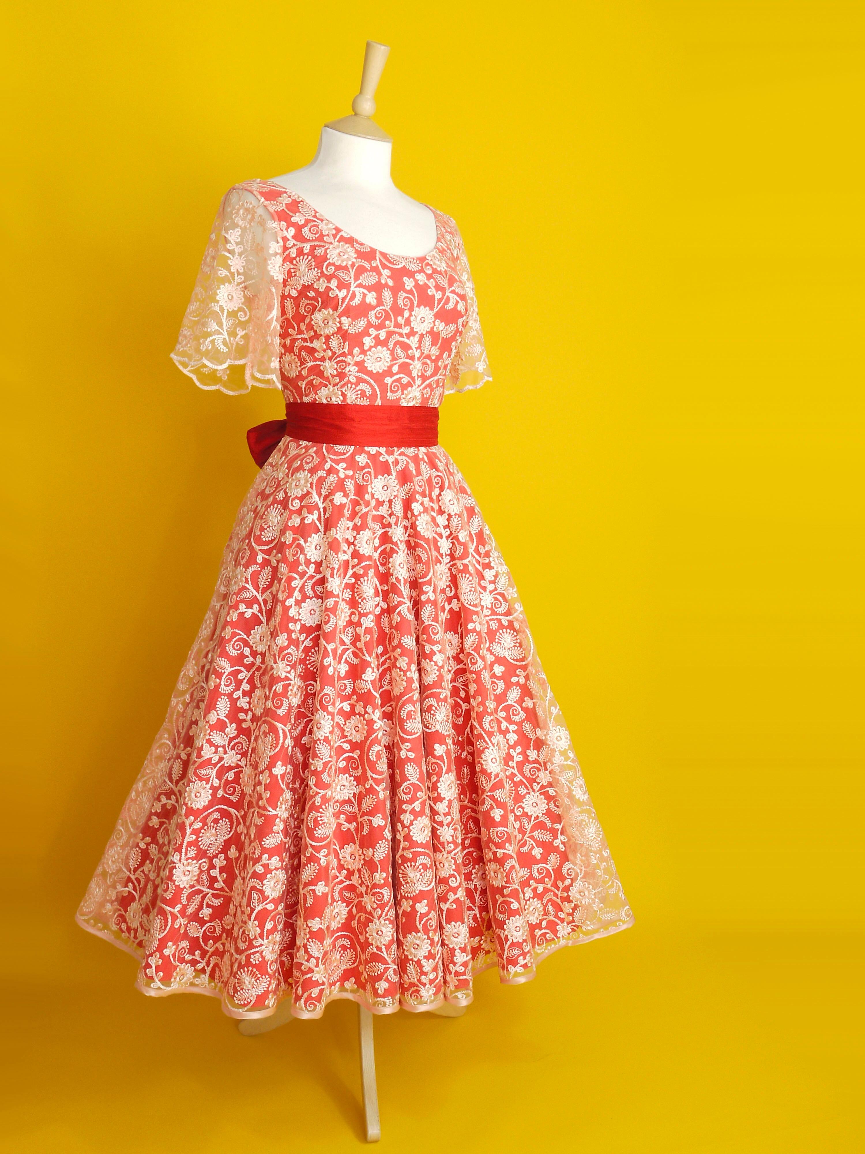 A red and peach lace dress with sleeves and a midi length circle skirt