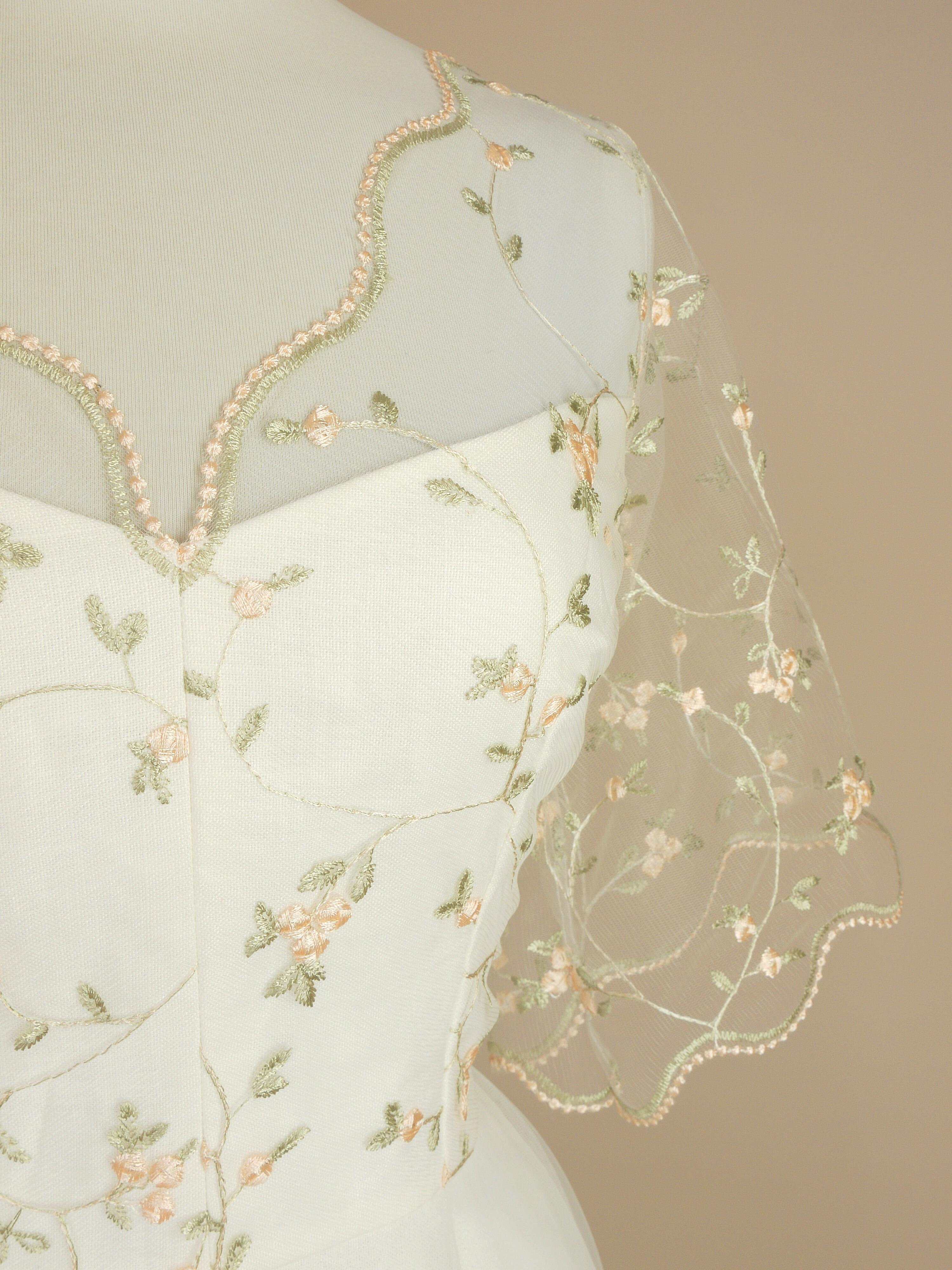a close up of the illusion v-neckline of the blossom wedding dress with delicate scalloped lace detailing