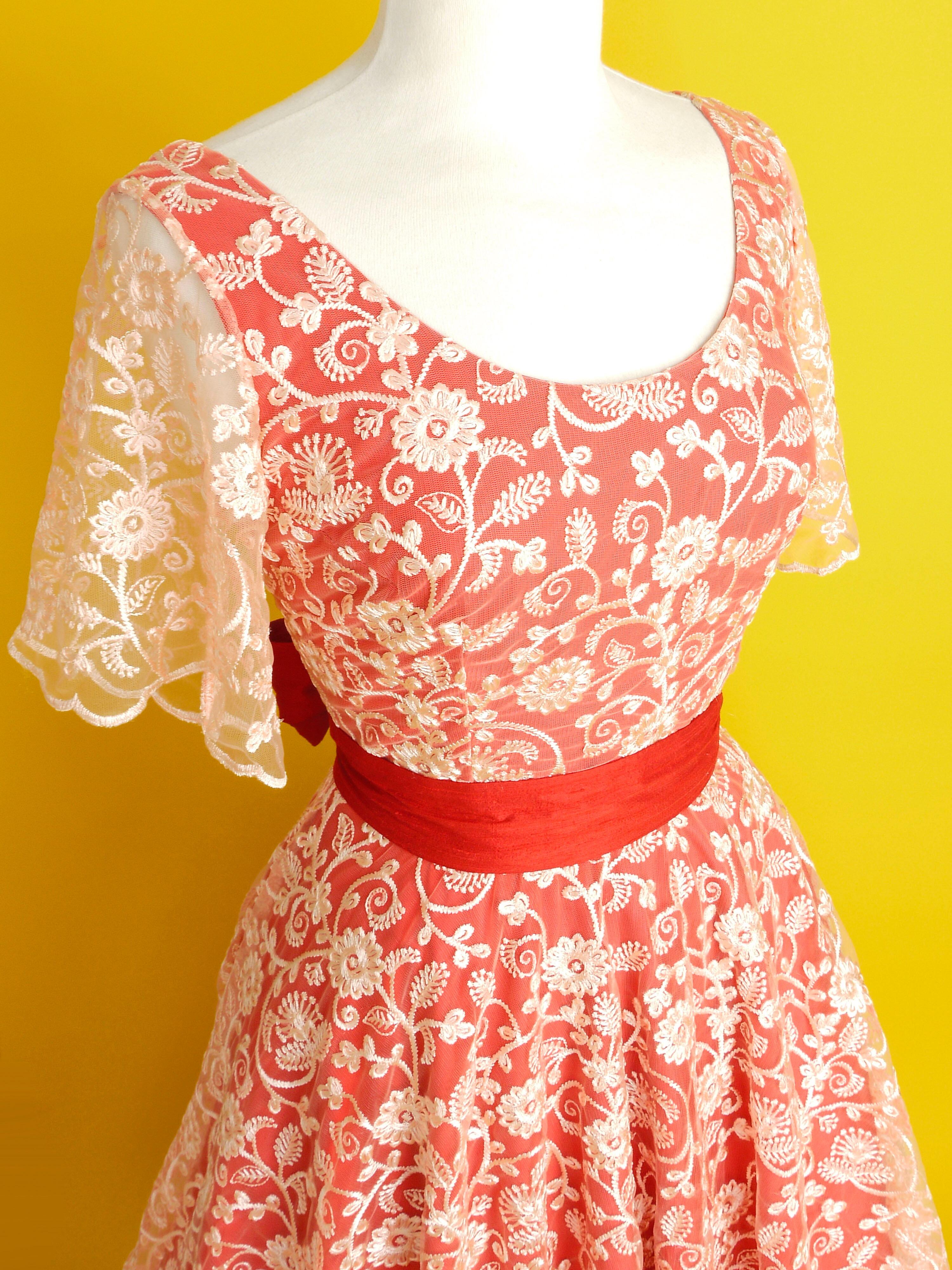 A red and peach lace dress with sleeves and a midi length circle skirt