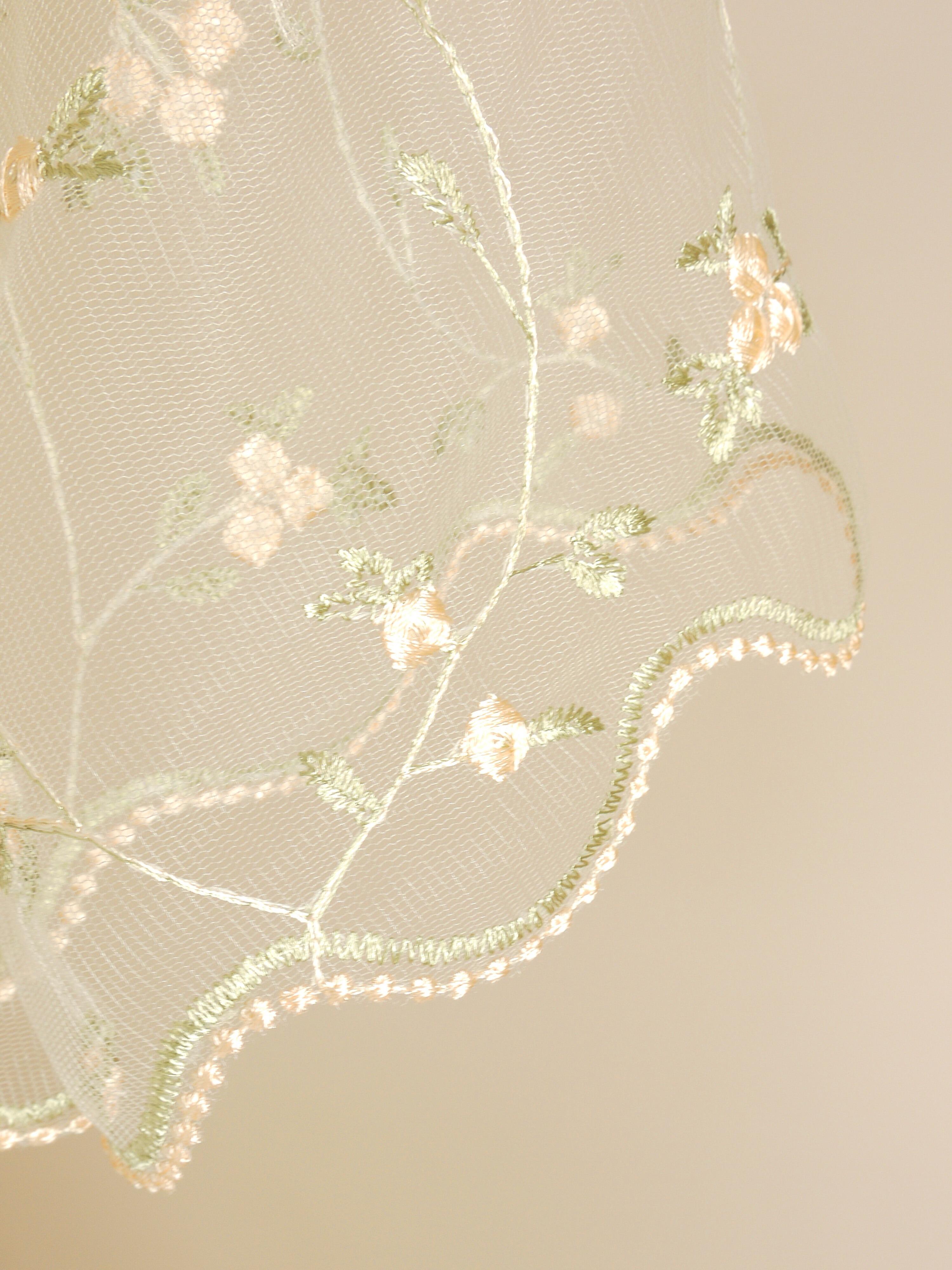 a close up of the exquisite blossom lace with subtle sage green and peach accents