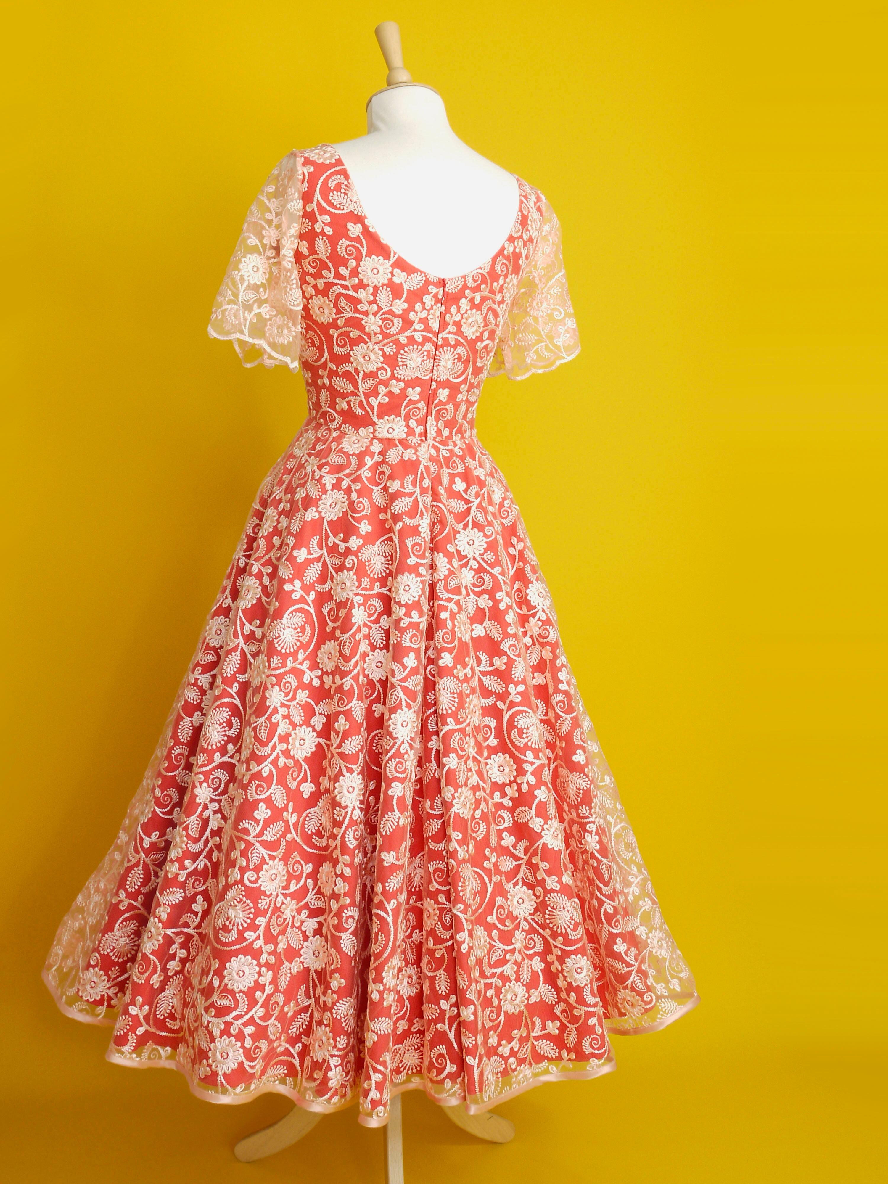 A red and peach lace dress with sleeves and a midi length circle skirt