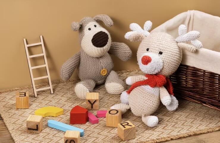 Two plush teddy bears surrounded by small toys on a brown play mat