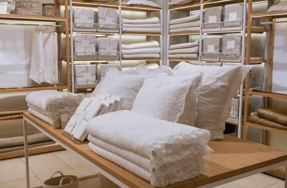 White pillows and assorted bedding products displayed on a wooden table