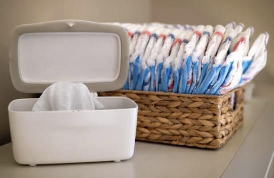 Brown basket filled with nappies and a pack of baby wipes on a table – Nappies & Wipes category AKNZ