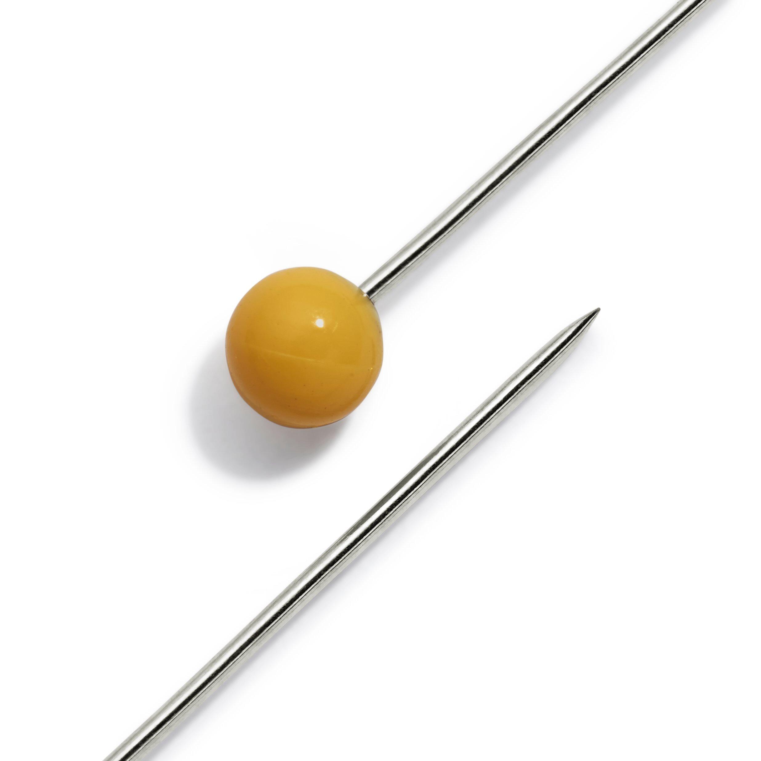 A close up look of a yellow plastic headed pin made by Prym