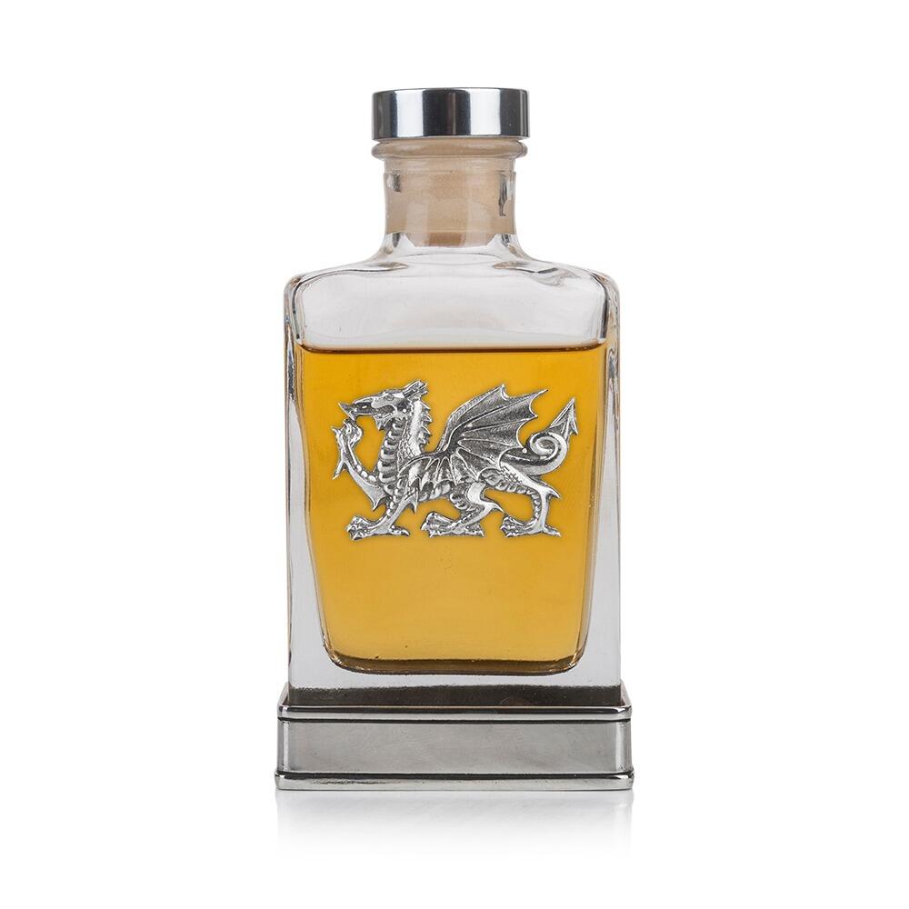 A glass flask with a pewter base and a handcrafted pewter Welsh Dragon emblem on the front