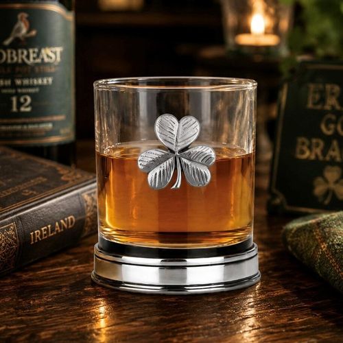 Whisky tumbler with pewter shamrock motif and polished base, partially filled with amber liquid