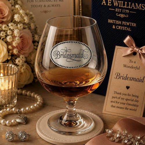 Crystal brandy snifter with pewter "Bridesmaid" badge, partially filled with amber liquid