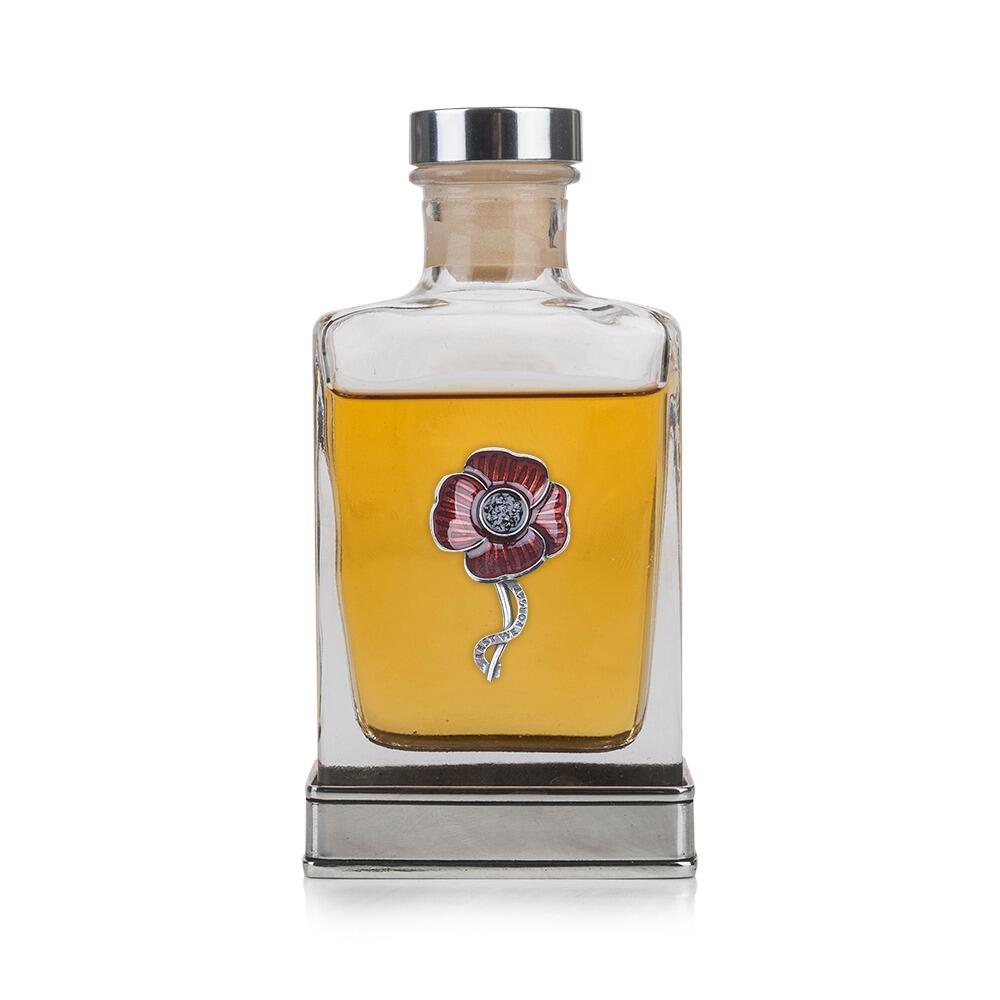 A glass flask with a pewter base and a handcrafted pewter poppy emblem on the front