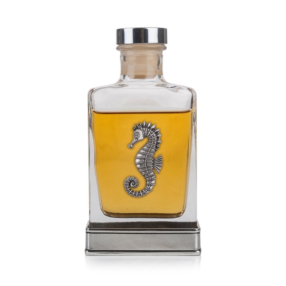 A glass flask with a pewter base and a handcrafted pewter seahorse emblem on the front