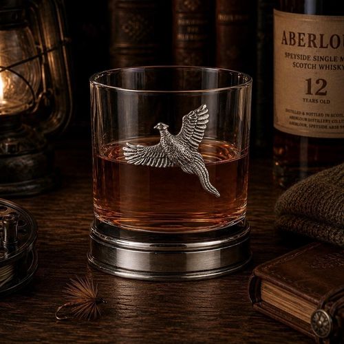 Whisky tumbler with pewter pheasant motif and polished base, partially filled with amber liquid