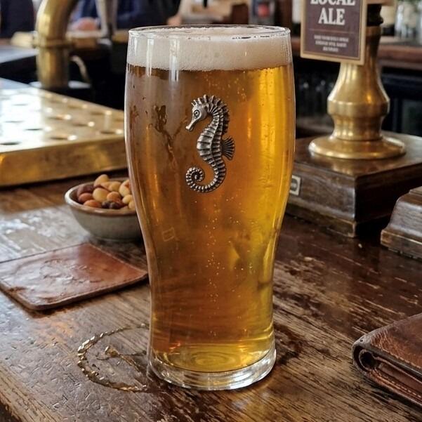 Pint glass with handmade pewter sea horse badge, filled with golden beer