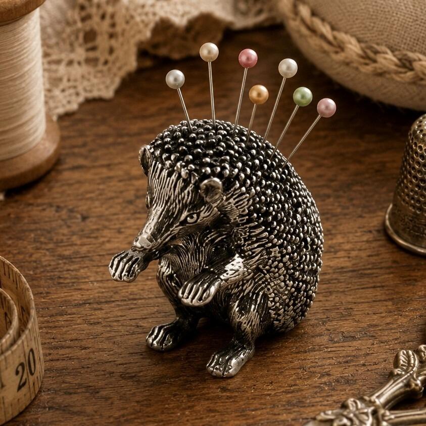 Vintage-style detailed pewter hedgehog pincushion figurine standing upright with several colorful pearl-head pins as quills