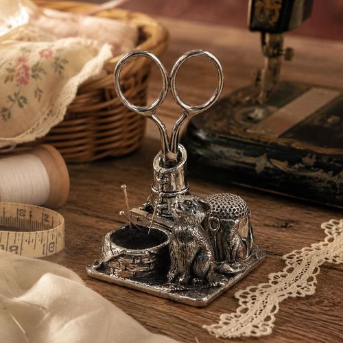 Vintage-style pewter cat sewing station featuring a detailed cat figurine, a boot-shaped scissor holder, a built-in thimble holder, and a small round pincushion