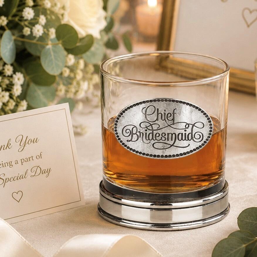 Whisky tumbler with pewter 'Chief Bridesmaid' badge and polished base, partially filled with amber liquid