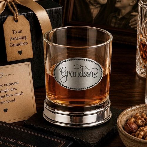 Whisky tumbler with pewter 'Grandson' badge and polished base, partially filled with amber liquid