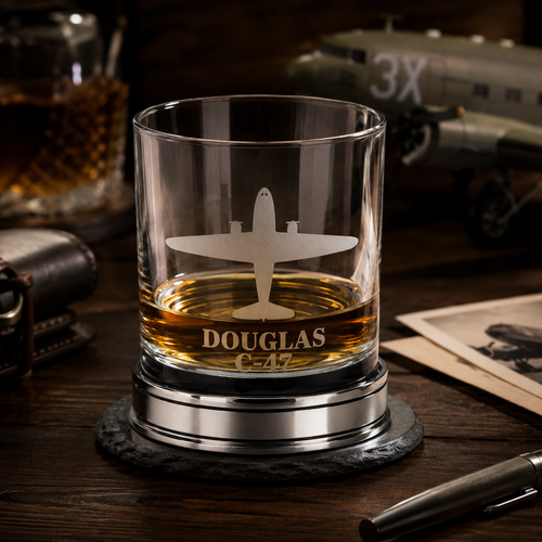 Handcrafted pewter Douglas C-47 Skytrain whisky tumbler, filled with whisky on a polished pewter base in a vintage WWII aircraft hangar setting, luxury British made aviation whisky glass gift