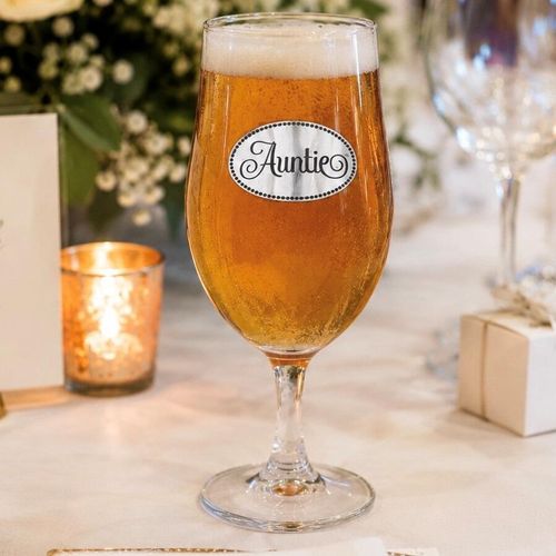 A Stemmed Pint Beer Glass with a Pewter Auntie badge on the front, filled with Beer