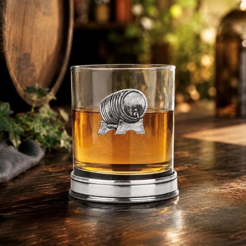 Whisky tumbler with pewter whisky barrel emblem and polished base, partially filled with amber liquid
