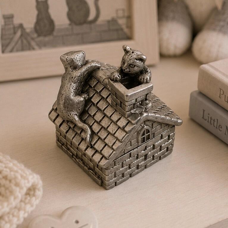 Pewter keepsake box shaped like a small house, featuring sculpted cat figurines with one cat climbing the tiled roof lid and another peeking out of the chimney