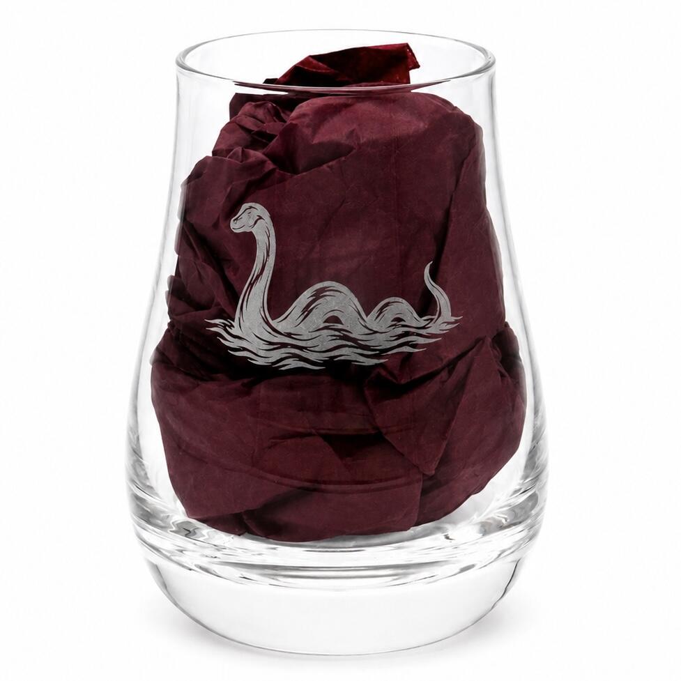 Close-up of Loch Ness Monster engraved whisky tasting glass with burgundy gift-box tissue