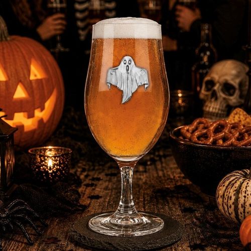 A stemmed beer glass filled with amber ale and a frothy head, featuring a detailed pewter ghost emblem on the front