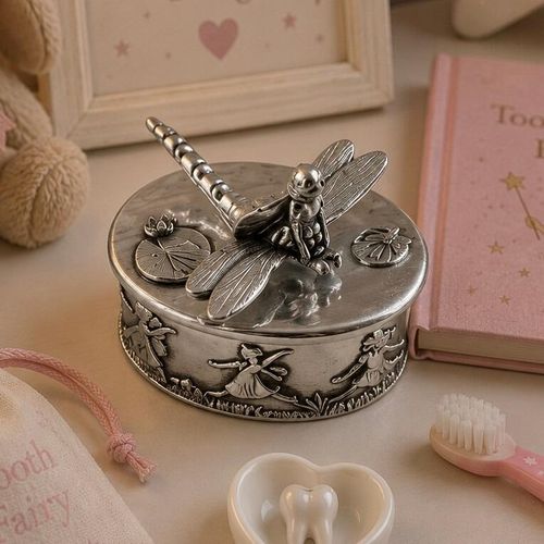 Oval pewter tooth fairy keepsake box with a sculpted dragonfly figurine and lily pads on the lid, decorated with a relief of dancing fairies around the base