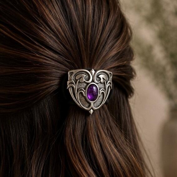 Shield-shaped pewter Art Nouveau style hair bobble featuring an oval purple faux-amethyst stone centered within flowing whiplash curves