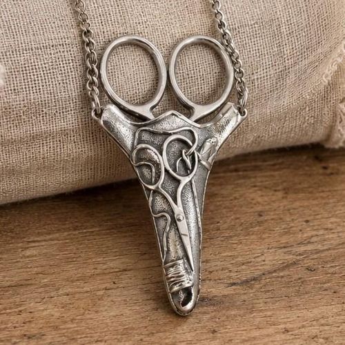 Vintage-style pewter scissor chatelaine sheath featuring embossed sewing motifs of scissors, a thimble, and a thread spool on a silver-toned chain