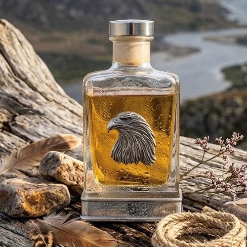 Glass whiskey flask featuring a pewter eagle head emblem and metal base