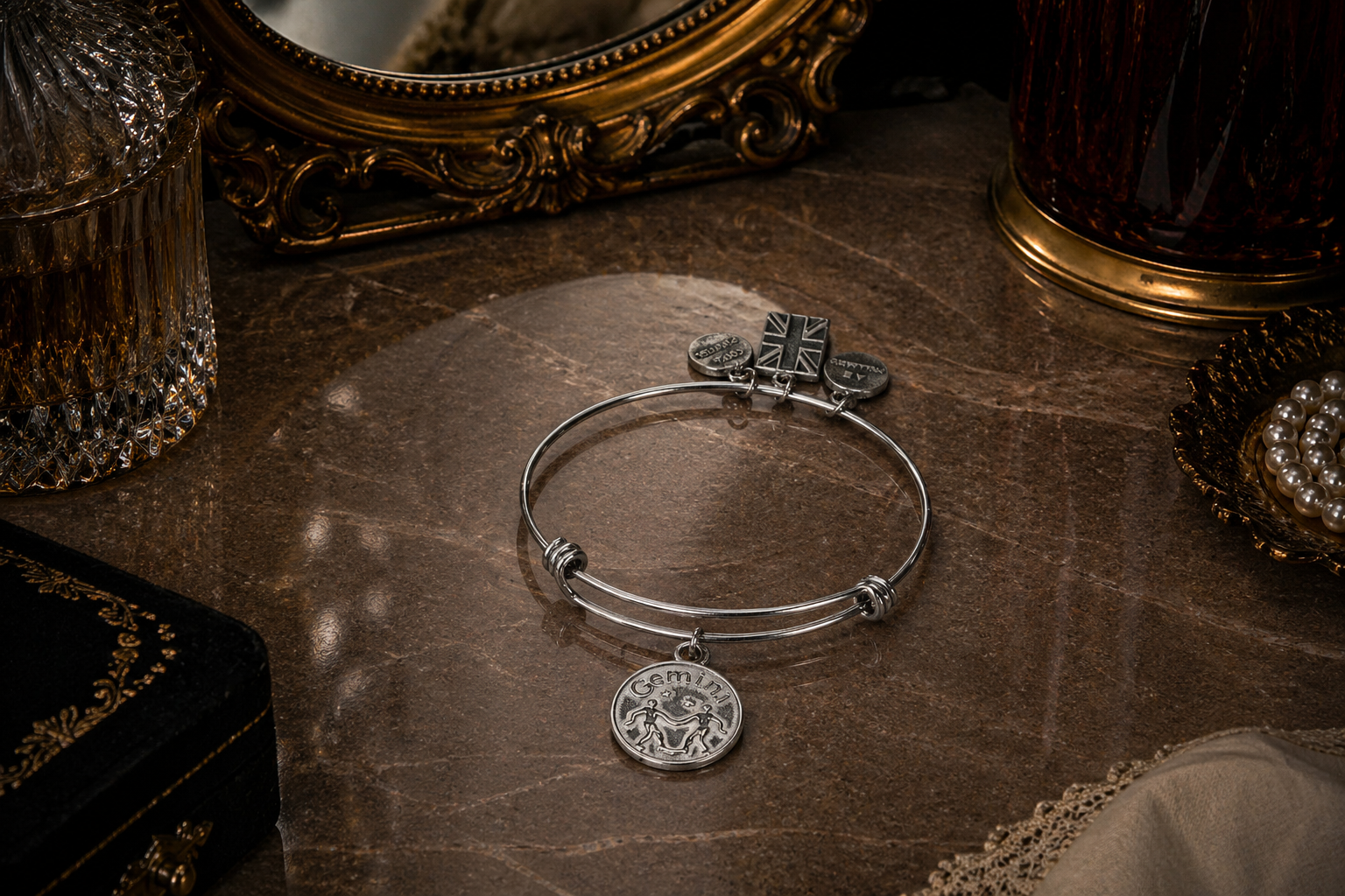 A pewter gemini charm on a bracelet shown on a vanity desk
