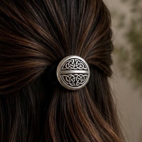 Round button-style pewter Celtic hair bobble featuring two semi-circular panels of tight, intricate knotwork divided by a smooth central bar