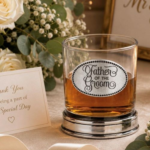 Whisky tumbler with pewter 'Father of the Groom' badge and polished base, partially filled with amber liquid