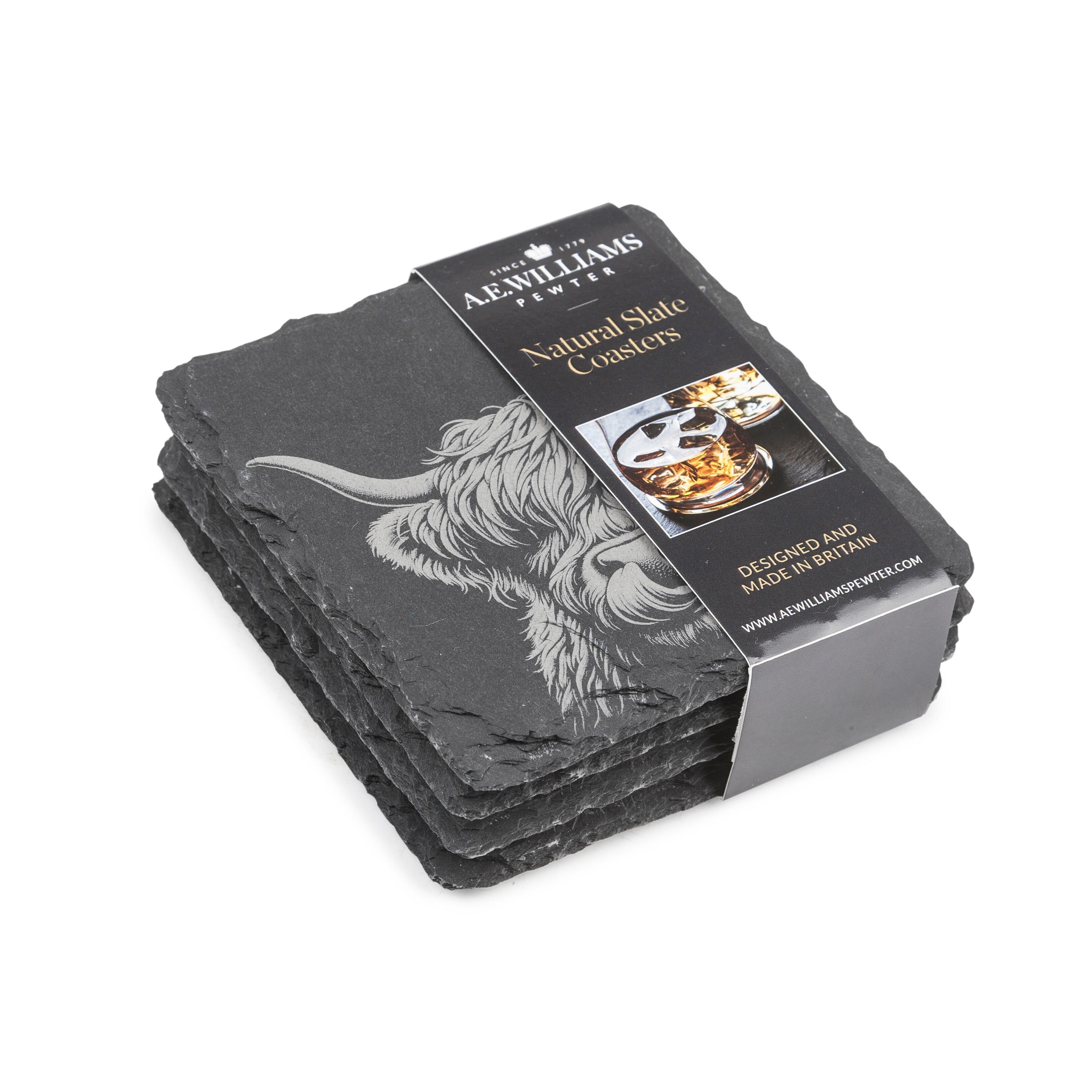 The top coaster features an engraved Highland Cow design. A product label wraps around the stack, displaying the brand name, product type 'Natural Slate Coasters', and an image of a Wolf on a coaster. The label states 'Designed and Made in Britain' and includes the company website.