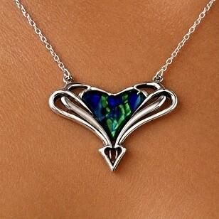 An Archibald Knox style pewter pendant with asymmetric Art Nouveau openwork wings and a central heart-shaped inlay of vibrant blue and green enamel