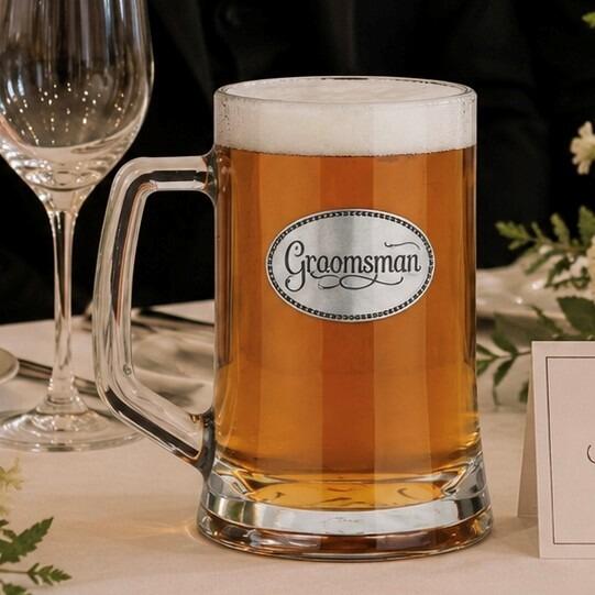 A Beer Tankard with a Pewter Groomsman badge on the front, filled with Amber Beer