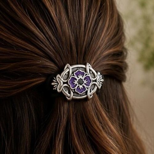 Elongated pewter Archibald Knox style hair bobble featuring a central purple enamel flower motif surrounded by intricate Celtic knotwork curves
