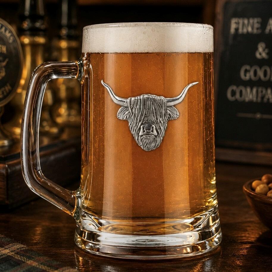 A Beer Tankard with a Pewter Highland Cow badge on the front, filled with Amber Beer