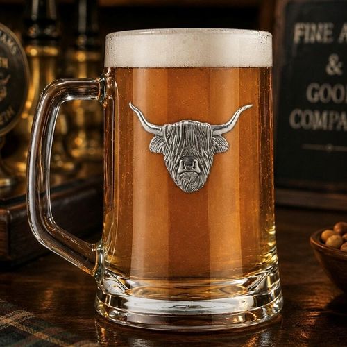 A Beer Tankard with a Pewter Highland Cow badge on the front, filled with Amber Beer