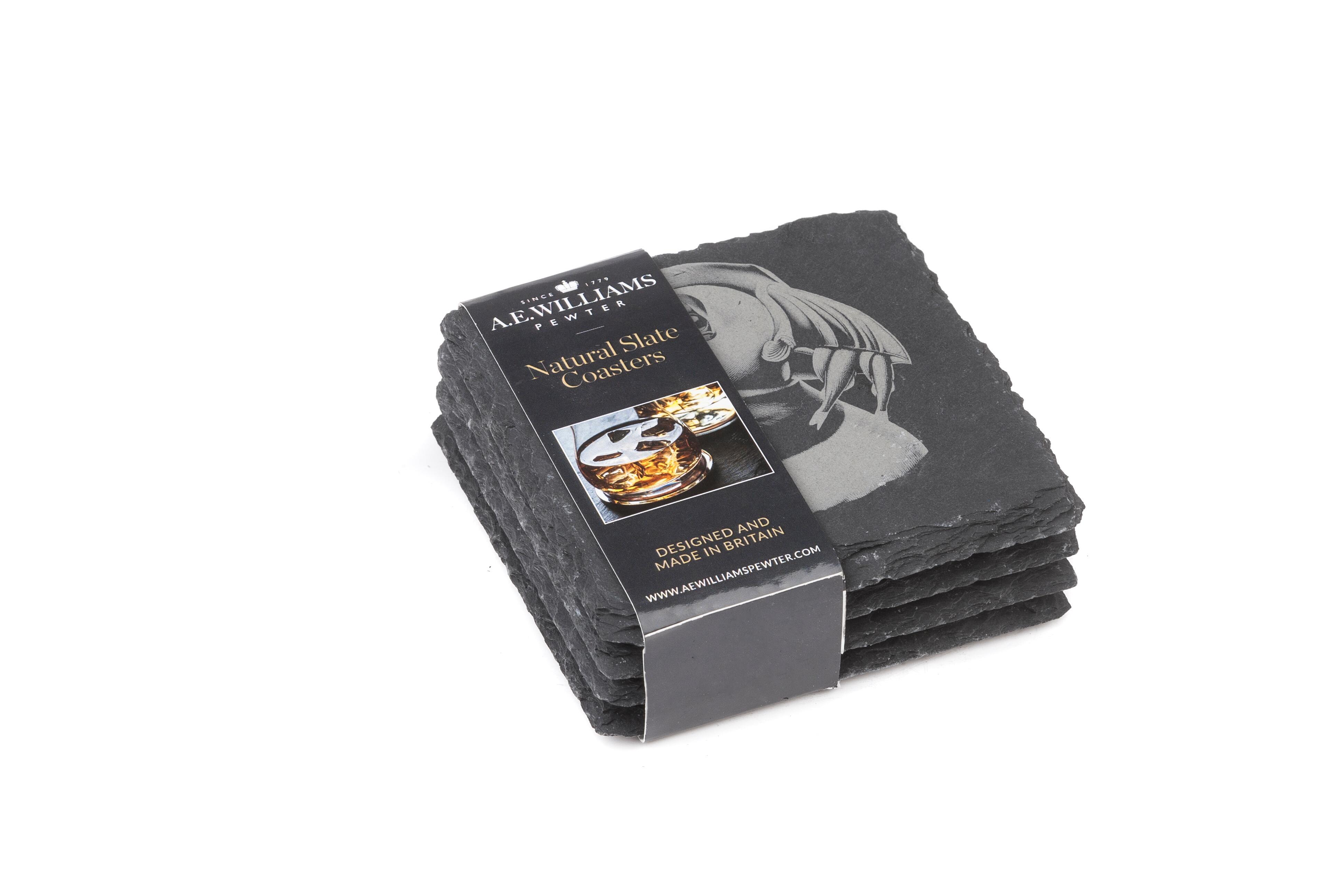 The top coaster features an engraved Puffin design. A product label wraps around the stack, displaying the brand name, product type 'Natural Slate Coasters', and an image of a Stag on a coaster. The label states 'Designed and Made in Britain' and includes the company website.