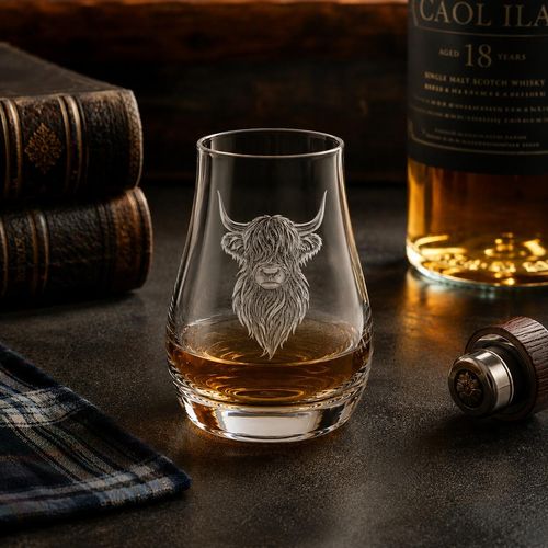 Highland cow engraved whisky tasting glass with Scotch whisky in a rustic distillery setting