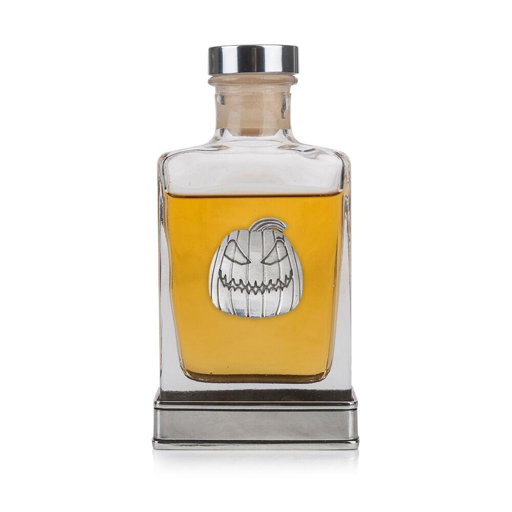 A glass flask with a pewter base and a handcrafted pewter pumpkin emblem on the front