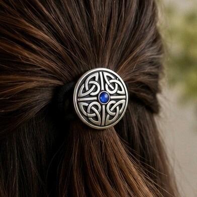 Circular pewter Celtic knotwork hair bobble featuring a small, round blue faux-sapphire gemstone in the center