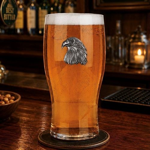Pint glass with handmade pewter eagle badge featuring spread wings filled with golden beer.