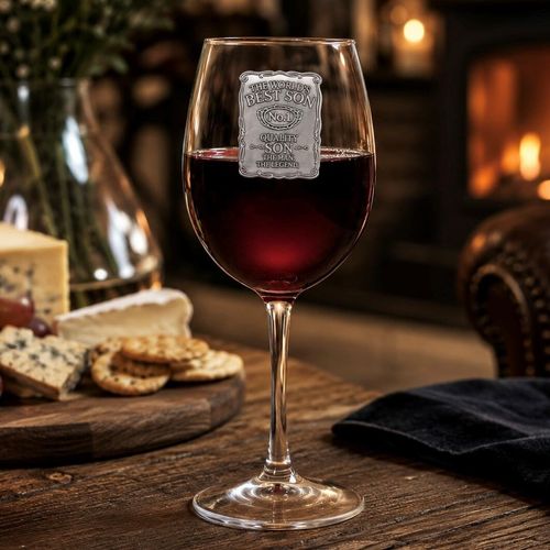 Wine glass filled with red wine, featuring a decorative pewter badge engraved with "The World's Best Son