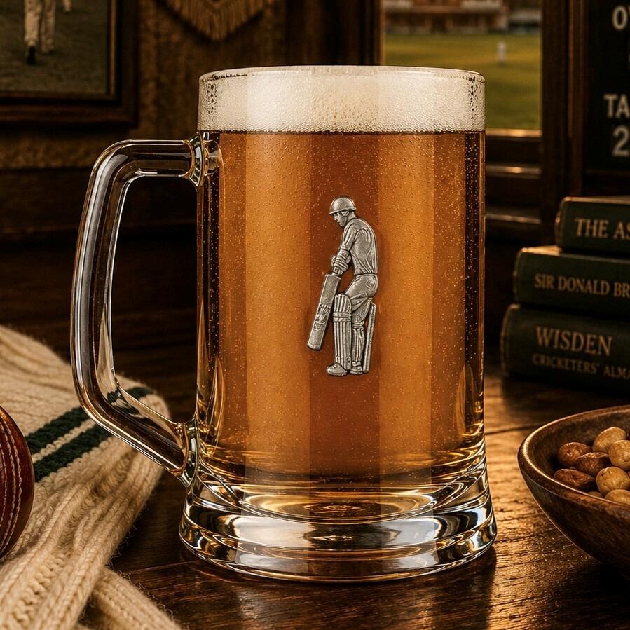 A Beer Tankard with a Pewter Cricketer badge on the front, filled with Amber Beer