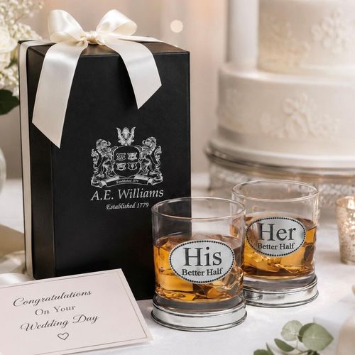 Set of two whisky tumblers with pewter "His Better Half" and "Her Better Half" badges and polished bases, partially filled with amber liquid